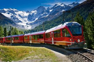 Der Zug der Rhätischer Bahn - Bernina Express, in der Gegend des Bernina Bergmassivs und des Morteratschgletscher.