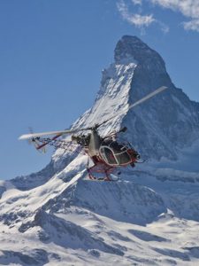 Ein Hubschrauber fliegt vor dem Berg Matterhorn.